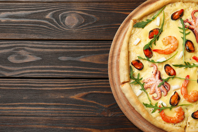 Photo of Delicious seafood pizza on wooden table, top view. Space for text
