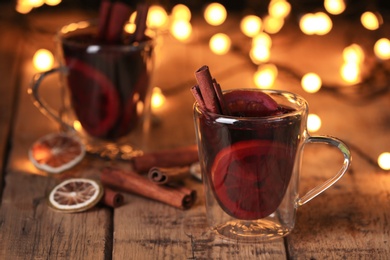 Mulled wine with cinnamon and orange on wooden table. Space for text