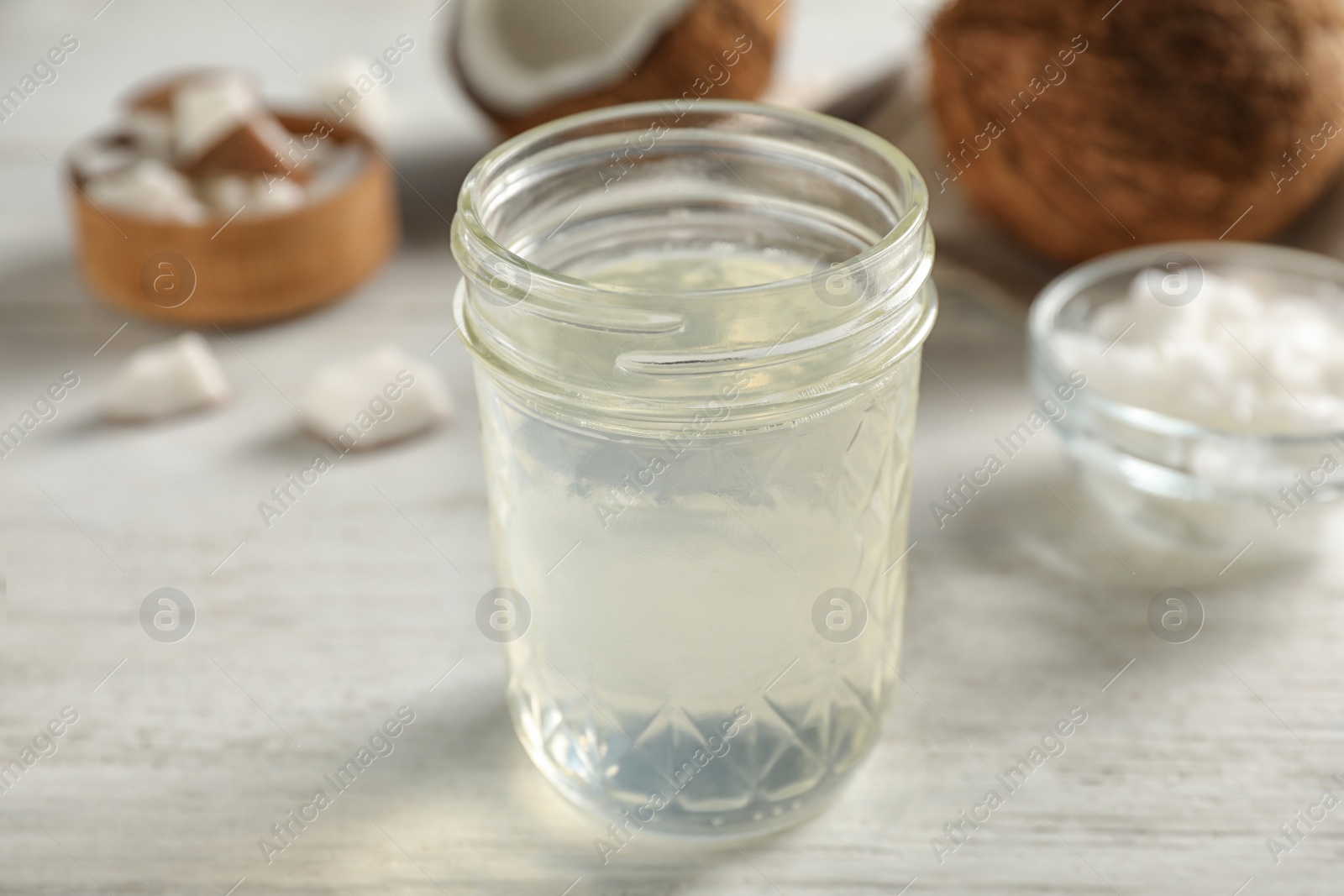 Photo of Coconut oil on white wooden table, closeup