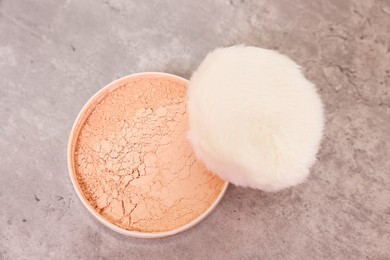Photo of Face powder with puff applicator on grey textured table, top view
