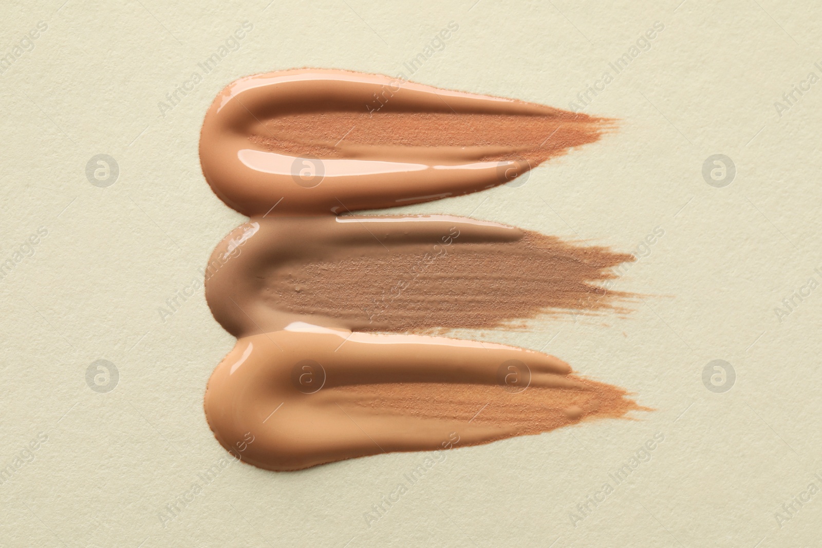 Photo of Samples of liquid skin foundations on beige background, top view