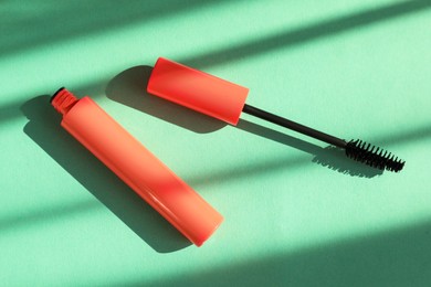 Photo of Mascara for eyelashes on mint background, flat lay. Makeup product