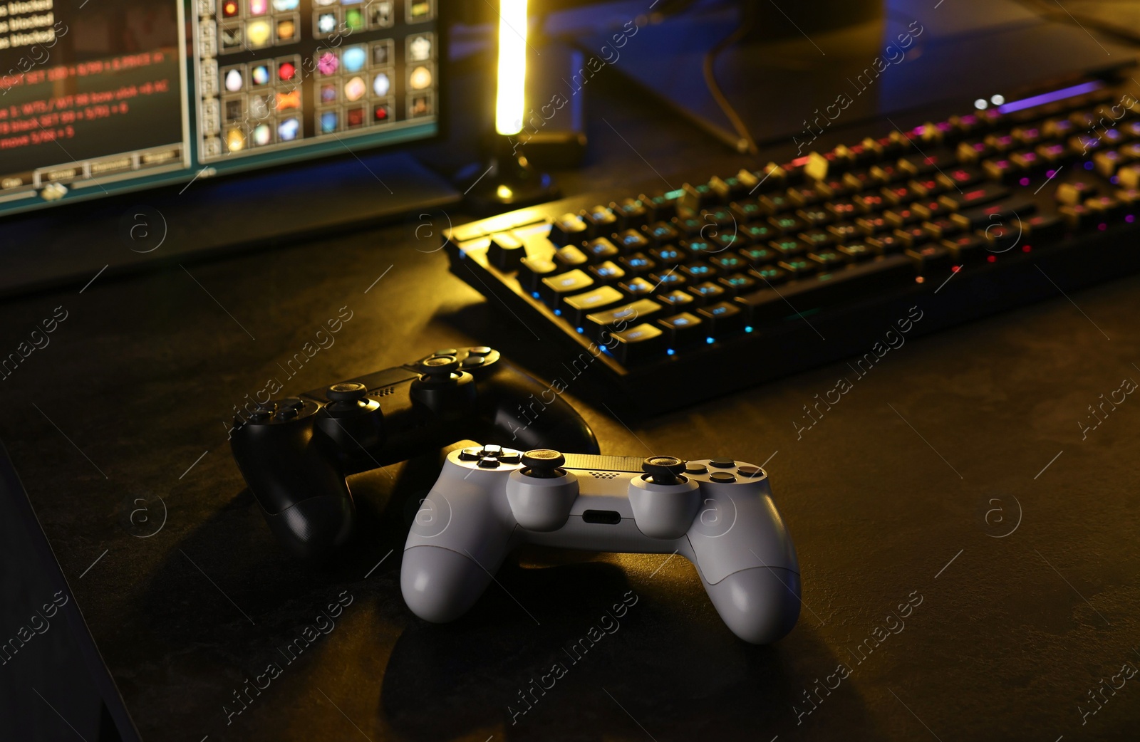 Photo of Playing video games. Computer monitor, keyboard and wireless controllers on table indoors