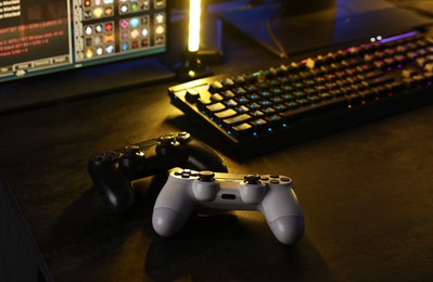 Playing video games. Computer monitor, keyboard and wireless controllers on table indoors