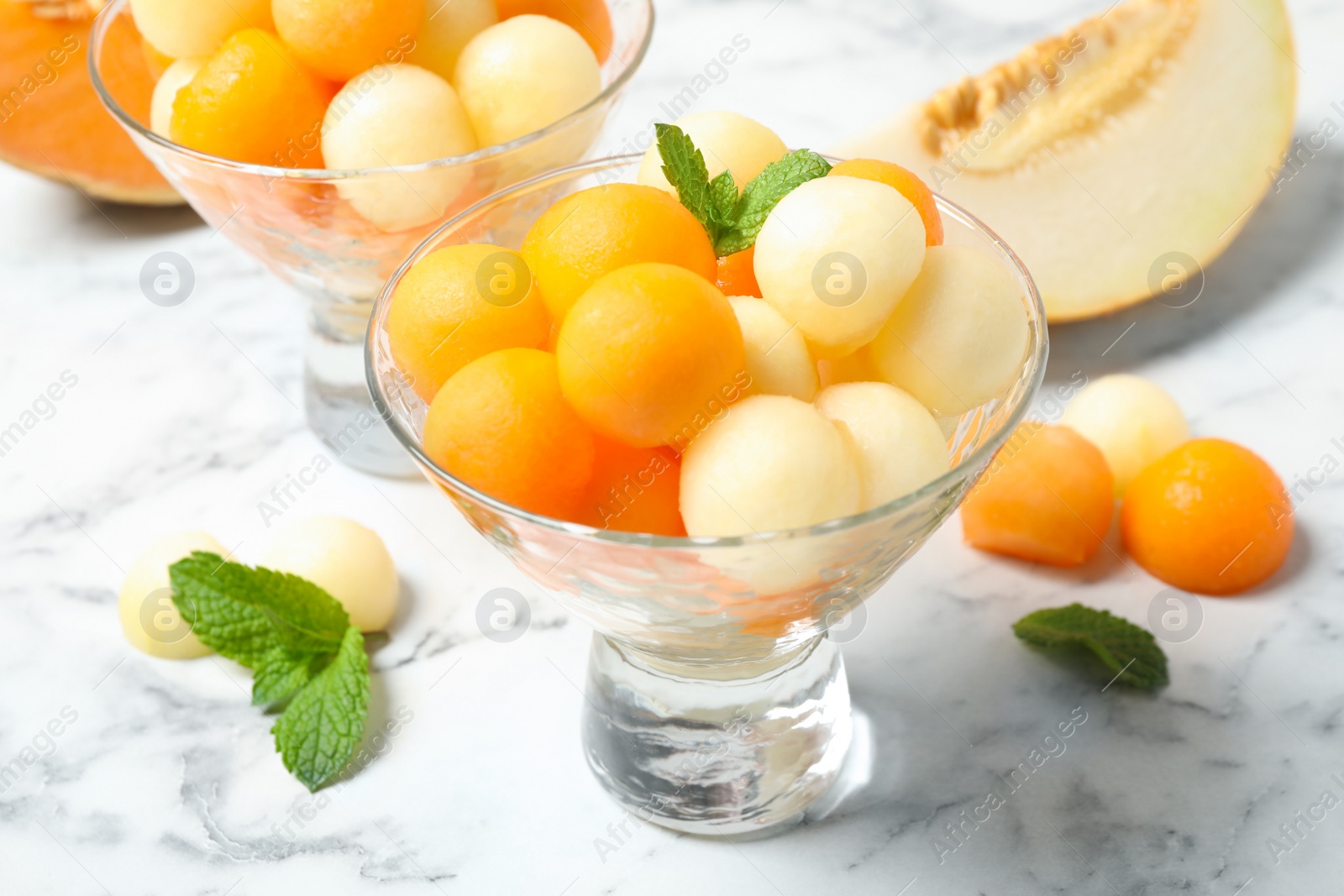 Photo of Melon balls and mint on white marble table, closeup