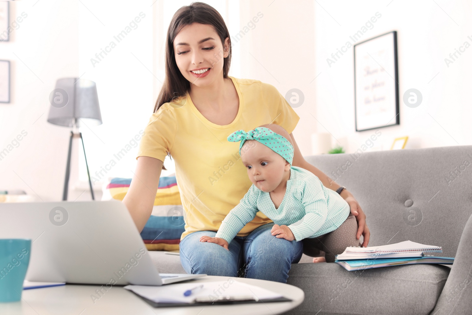 Photo of Young mother with her cute baby girl working at home