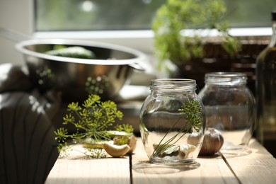 Photo of Empty glass jars and ingredients prepared for canning on wooden table indoors