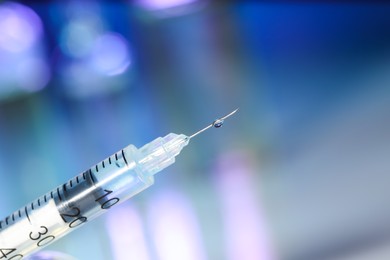 Syringe with medicine against blurred background, closeup. Space for text