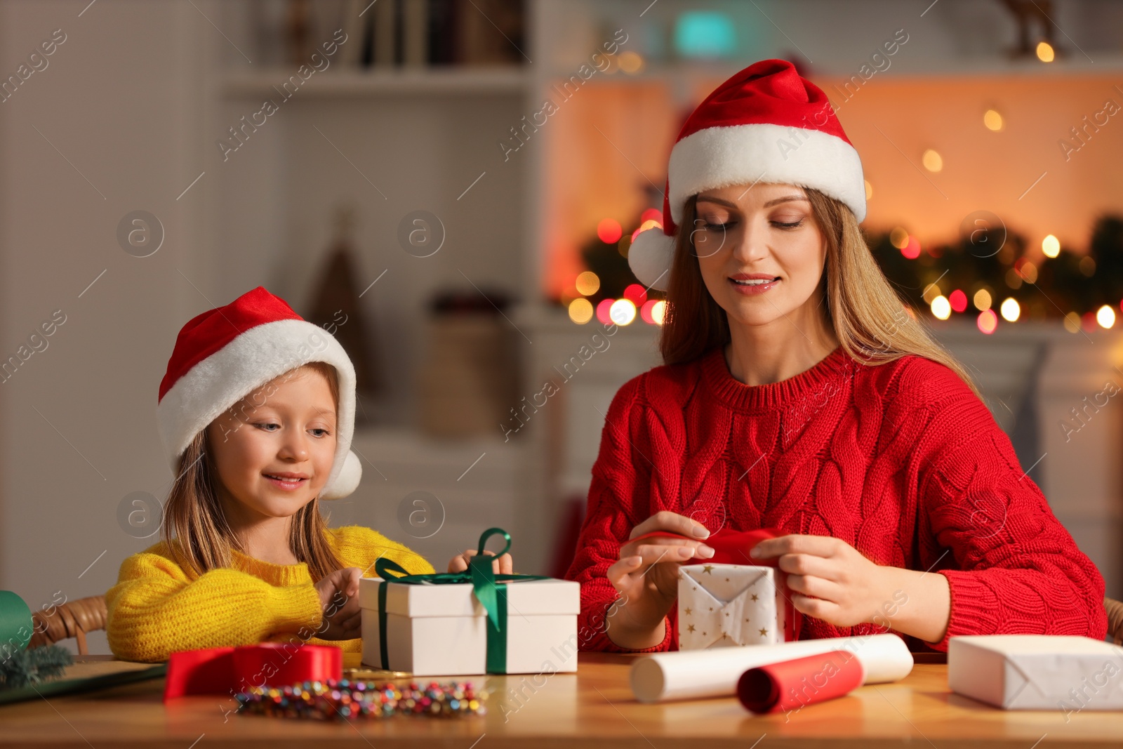 Photo of Christmas presents wrapping. Mother and her little daughter decorating gift boxes with ribbon at home