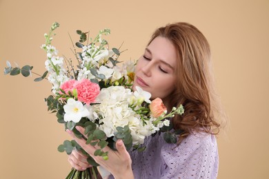 Beautiful woman with bouquet of flowers on beige background