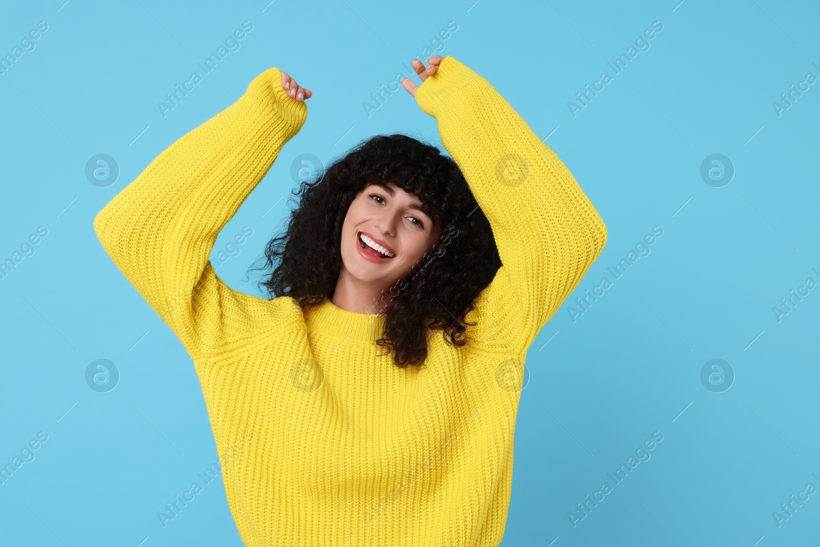 Photo of Happy young woman in stylish yellow sweater on light blue background