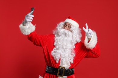 Photo of Merry Christmas. Santa Claus taking selfie on red background