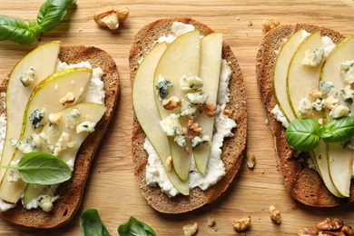 Photo of Delicious bruschettas with pear on wooden table, flat lay