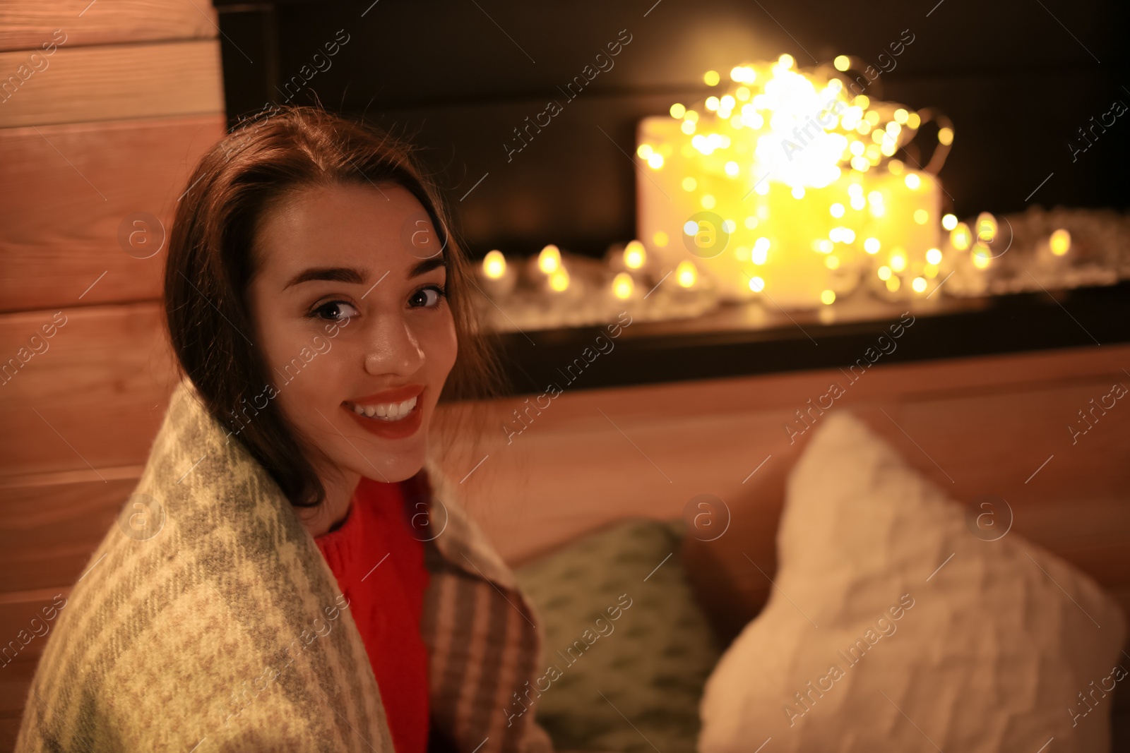 Photo of Young woman resting near decorative fireplace at home. Winter season