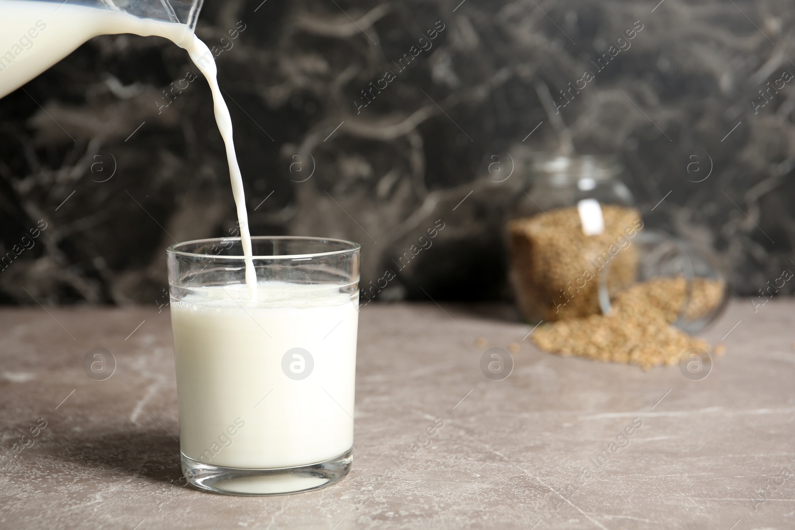 Photo of Pouring hemp milk into glass on table, closeup