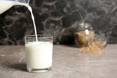 Photo of Pouring hemp milk into glass on table, closeup