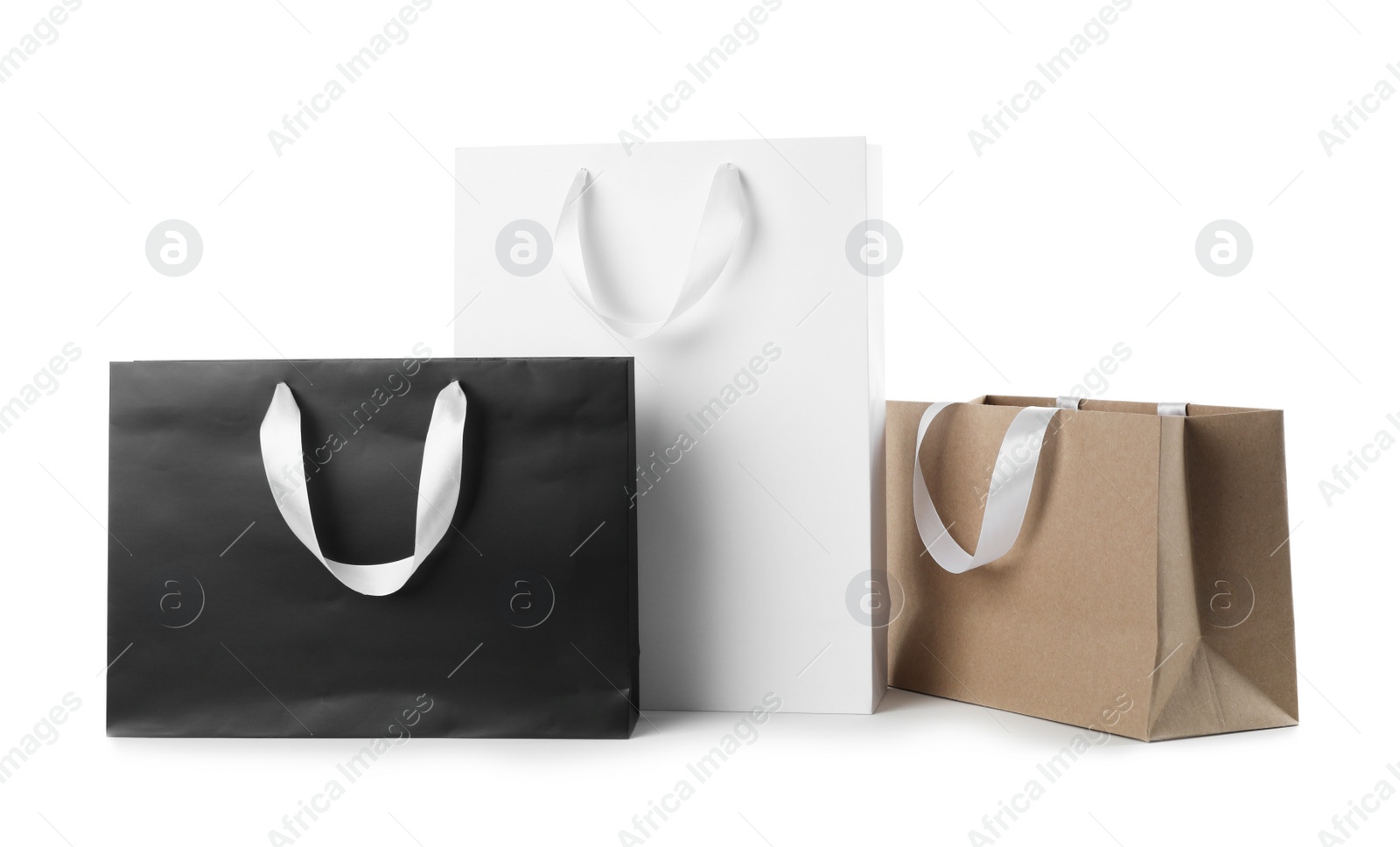 Photo of Paper shopping bags with ribbon handles on white background. Mockup for design