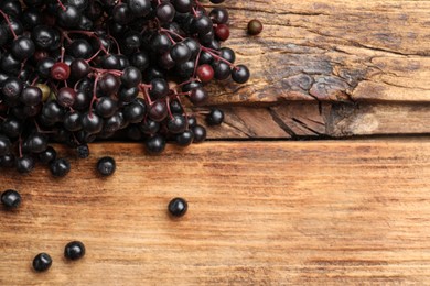 Photo of Elderberries (Sambucus) on wooden table, flat lay. Space for text