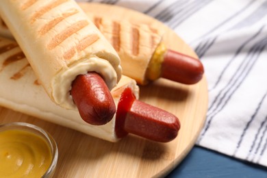 Tasty french hot dogs with different sauces on wooden board, closeup. Space for text