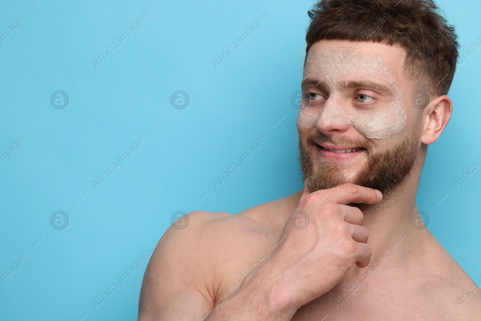 Photo of Handsome man with facial mask on his face against light blue background, space for text