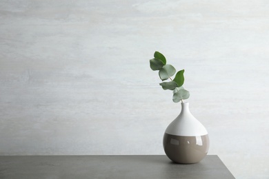 Photo of Vase with eucalyptus branch with fresh leaves on table