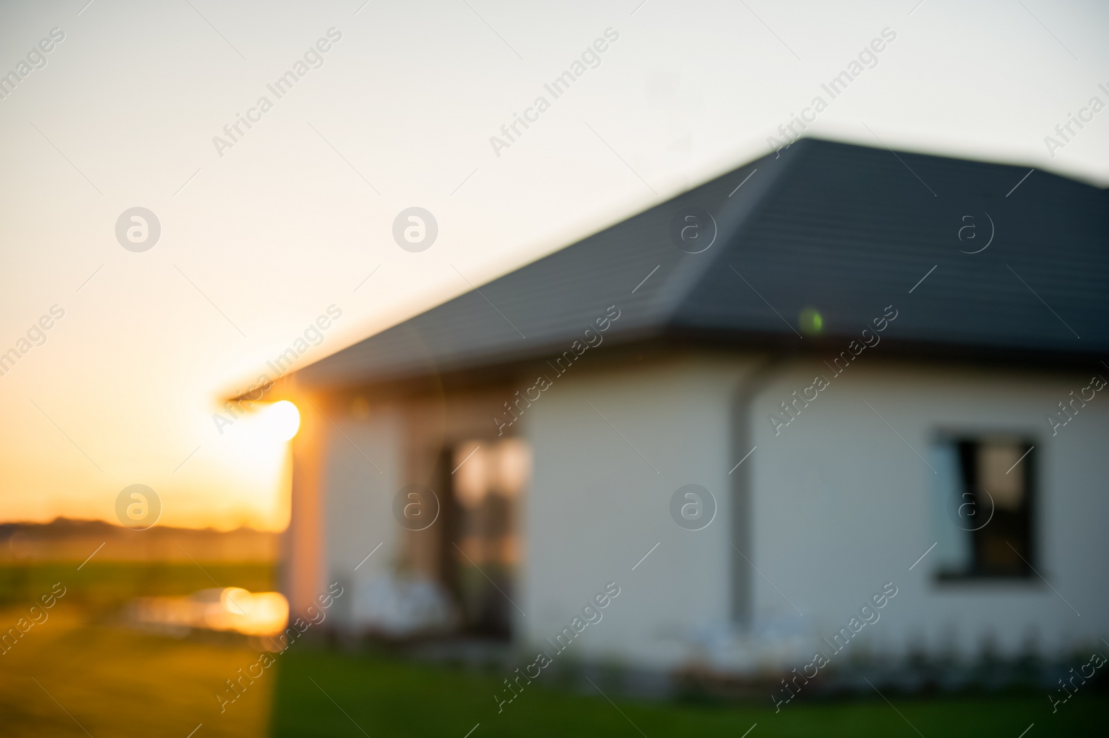 Photo of Blurred view of beautiful house with green lawn on sunny day