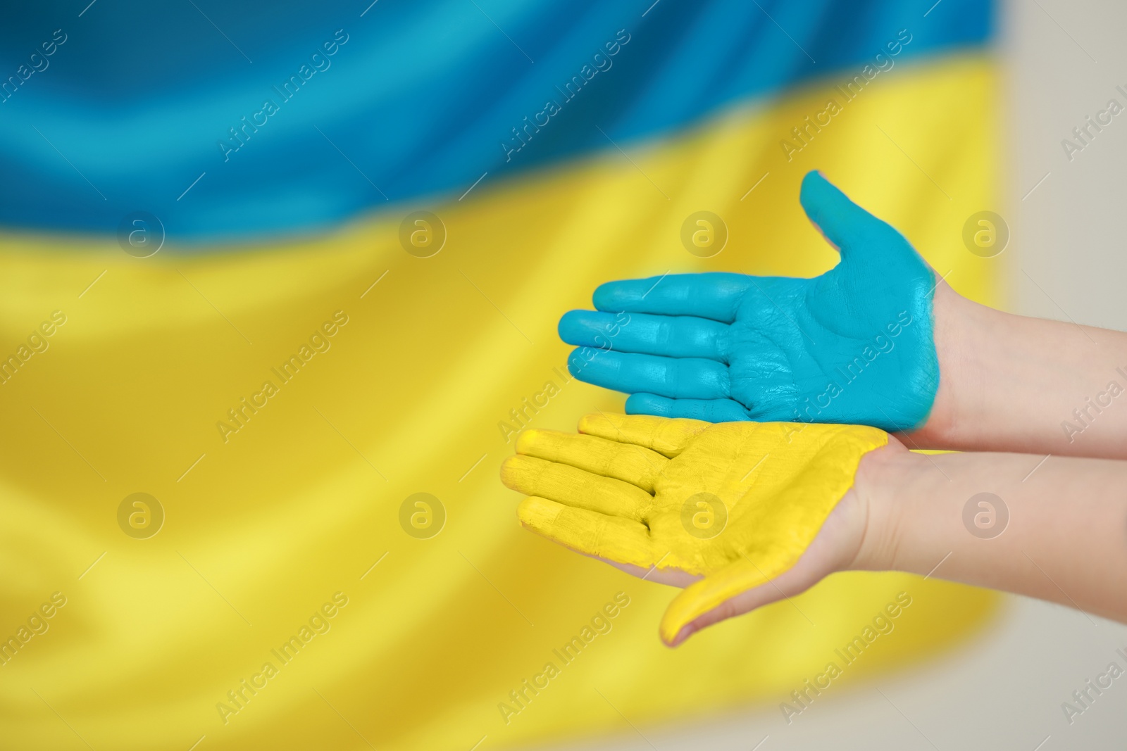 Photo of Little boy with painted hands near Ukrainian flag, closeup and space for text. Love Ukraine concept
