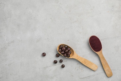 Spoons with acai powder and fresh berries on gray table, flat lay with space for text