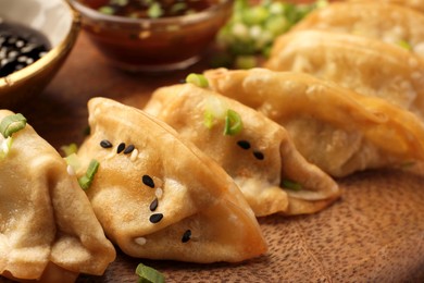 Photo of Delicious gyoza (asian dumplings) with sesame seeds and green onions on board, closeup