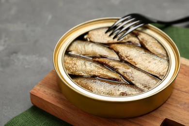 Canned sprats and fork on grey table, closeup. Space for text