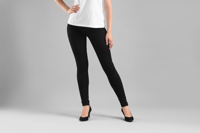 Photo of Woman wearing stylish black jeans and high heels shoes on light gray background, closeup