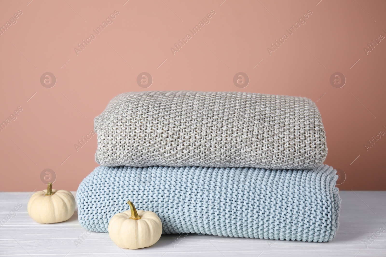 Photo of Soft plaids and small pumpkins on white wooden table, closeup