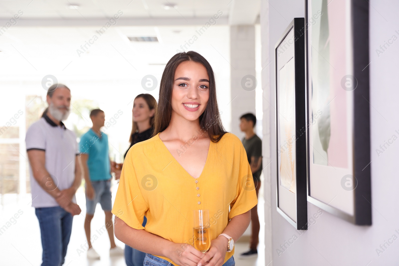 Photo of Young woman with glass of champagne at exhibition in art gallery