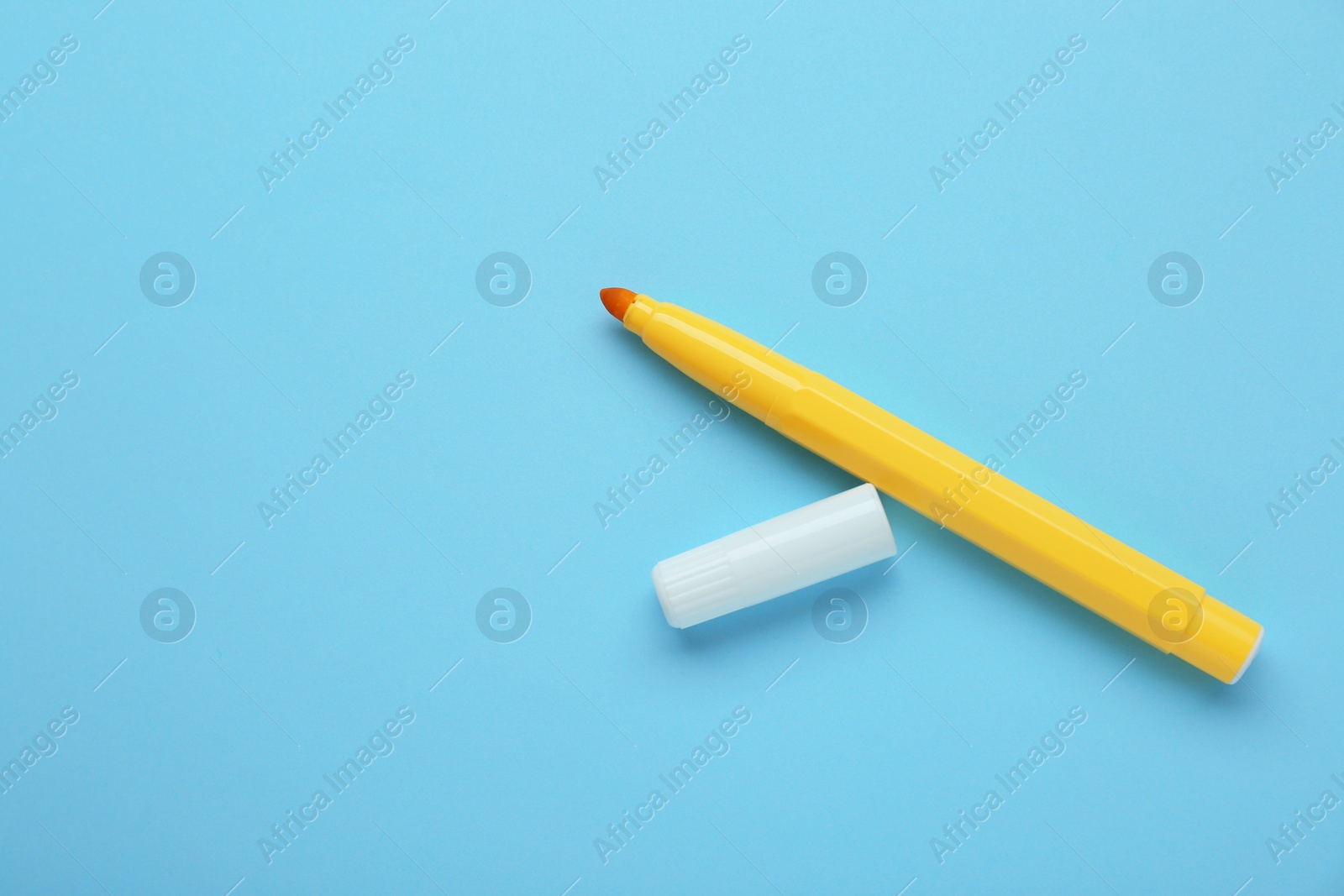 Photo of Bright yellow marker and cap on light blue background, flat lay. Space for text