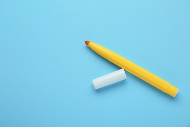 Photo of Bright yellow marker and cap on light blue background, flat lay. Space for text