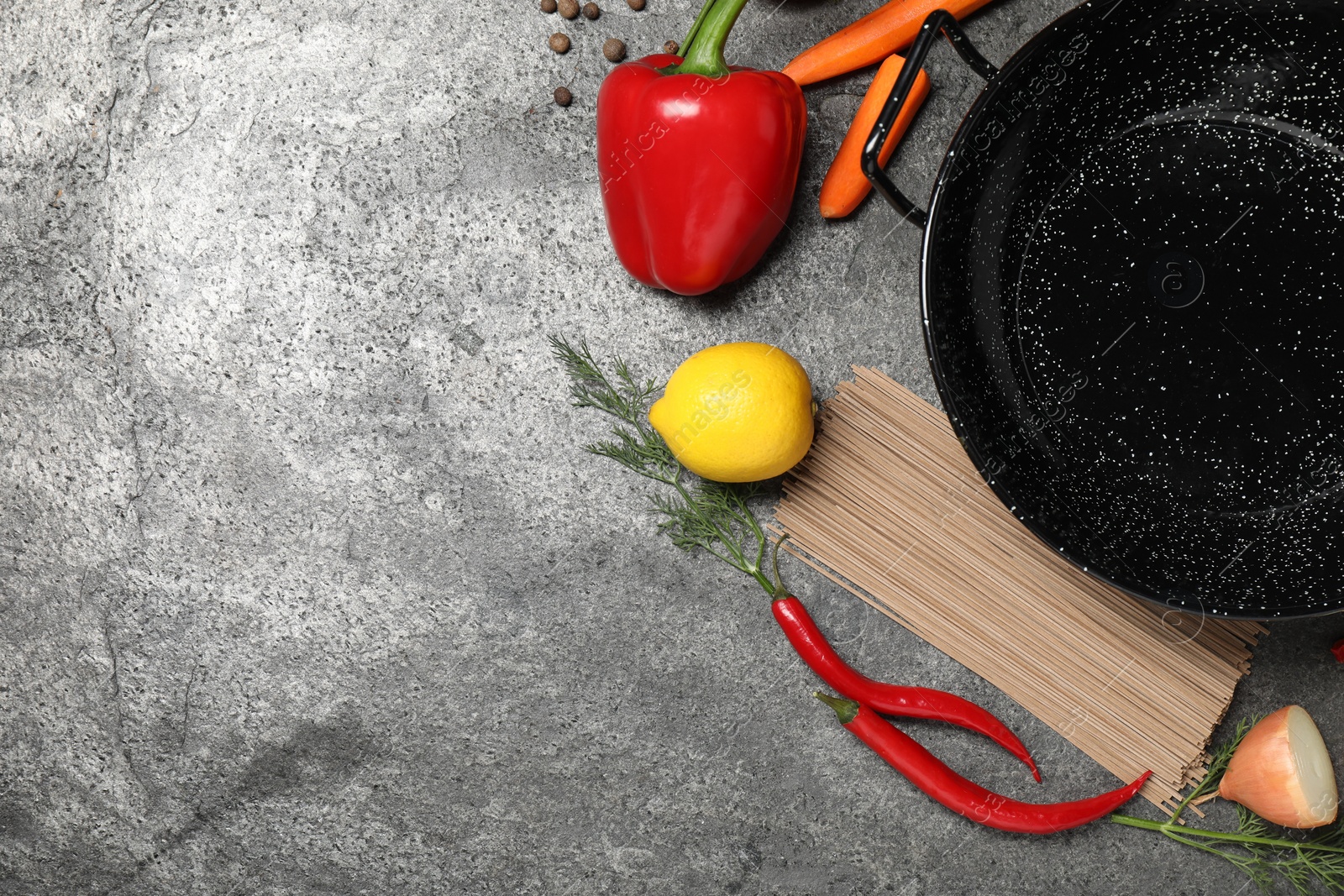 Photo of Empty iron wok and raw ingredients on grey table, flat lay. Space for text