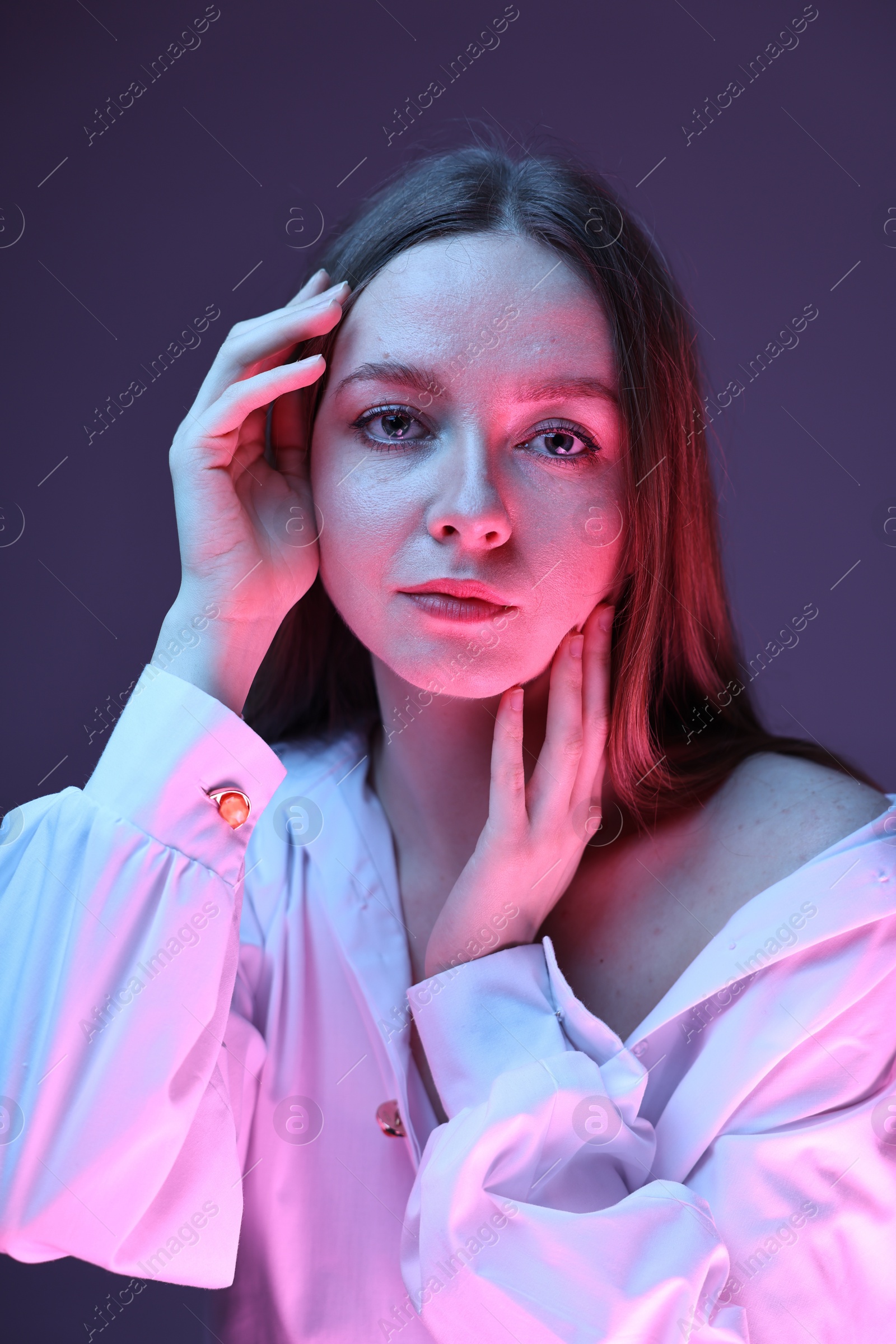 Photo of Fashionable portrait of beautiful young woman on purple background in neon lights