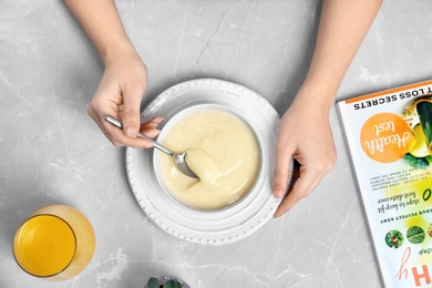 Photo of Woman with vanilla pudding at table, closeup