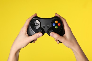 Photo of Woman using game controller on yellow background, closeup