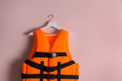 Orange life jacket on pink background. Personal flotation device