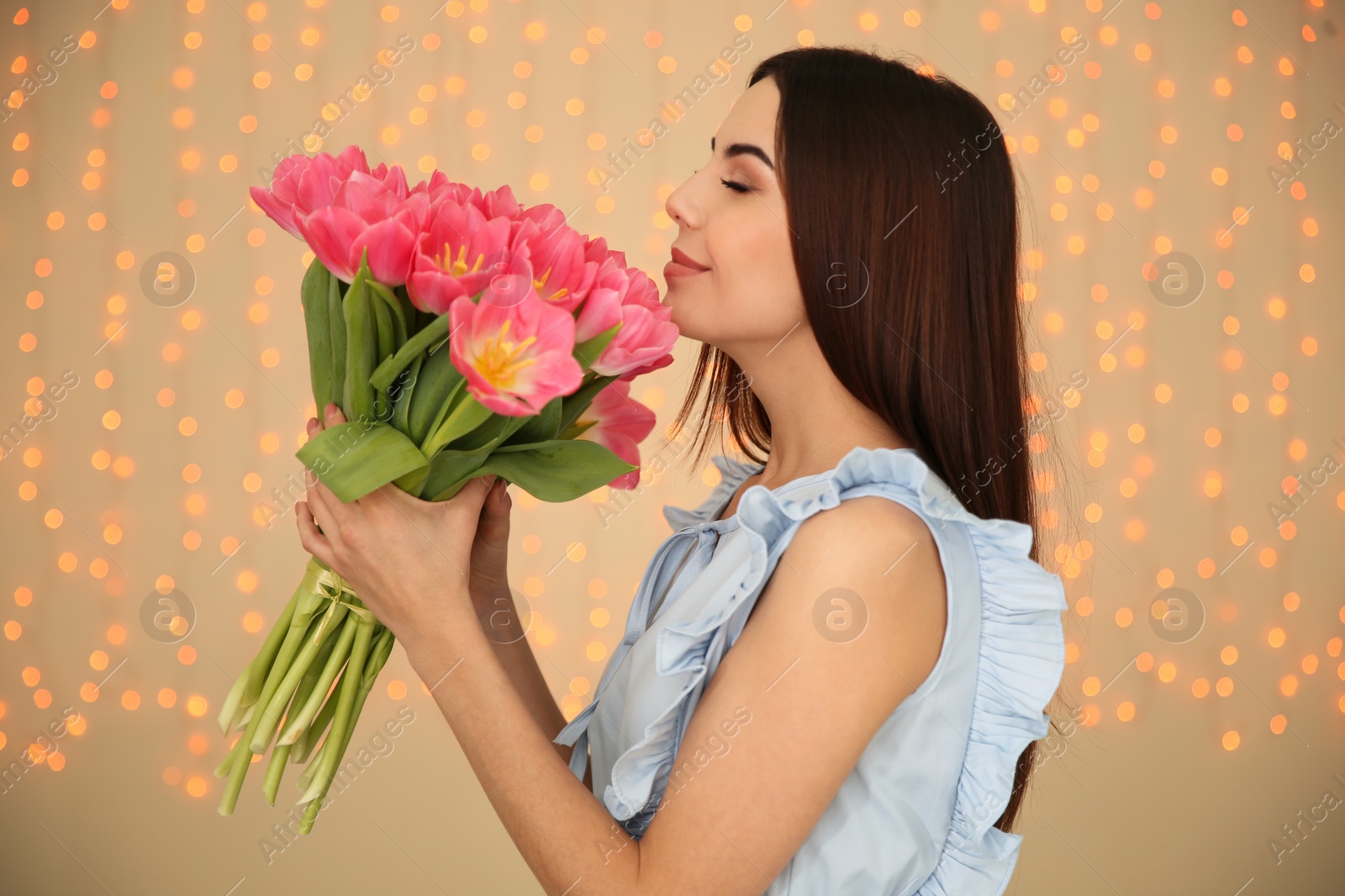 Photo of Portrait of smiling young girl with beautiful tulips on blurred background. International Women's Day