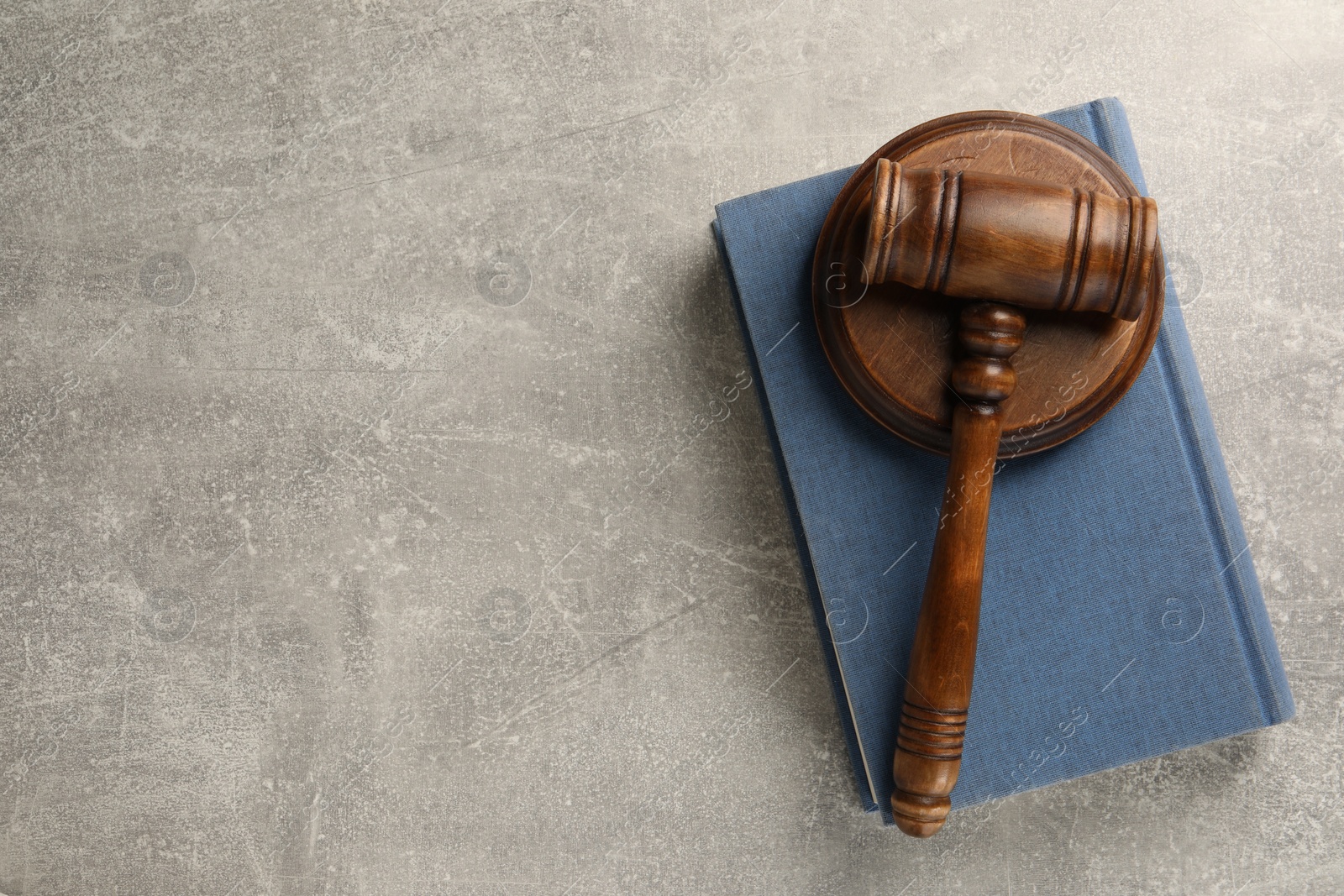 Photo of Wooden gavel, sound block and book on grey textured table, top view. Space for text