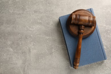 Wooden gavel, sound block and book on grey textured table, top view. Space for text