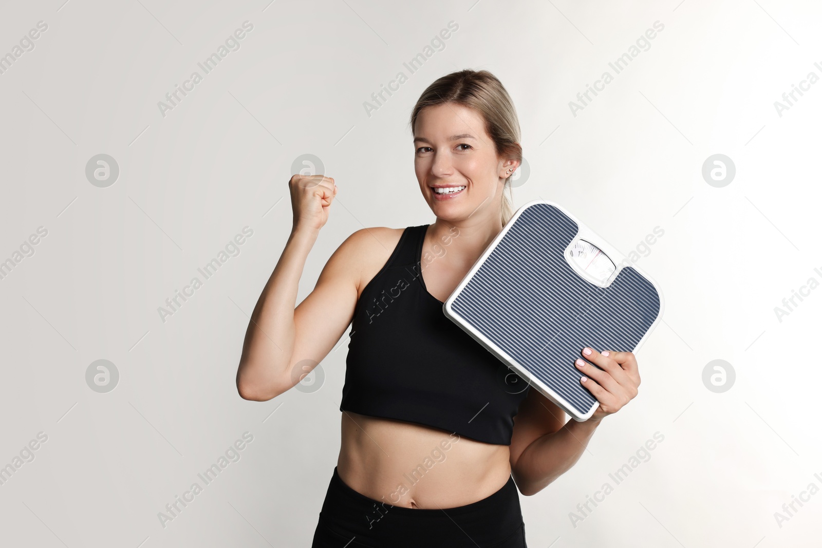 Photo of Woman in sportswear with scales on gray background