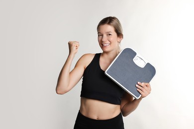 Photo of Woman in sportswear with scales on gray background