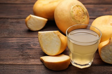 Photo of Glass of freshly made turnip juice on wooden table, space for text