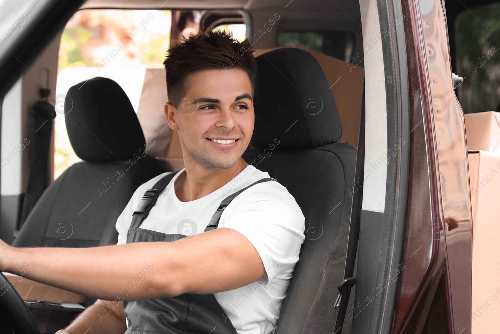 Photo of Young courier with smartphone in delivery car