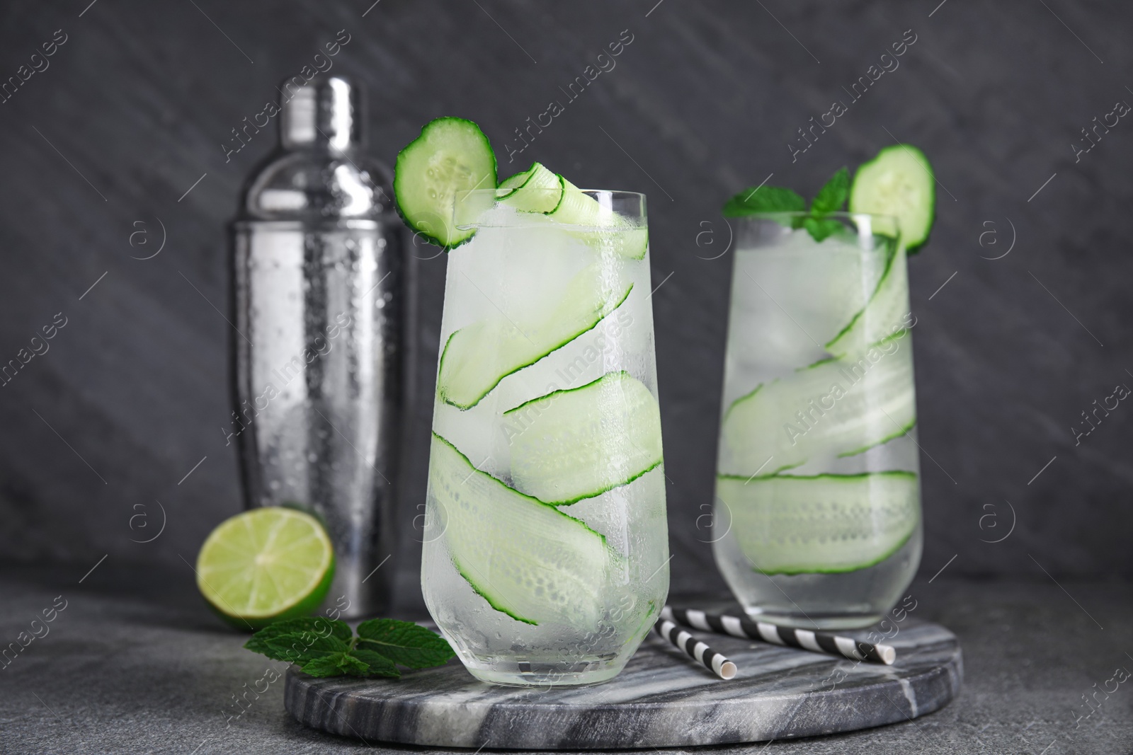Photo of Glasses of refreshing cucumber water on dark grey table