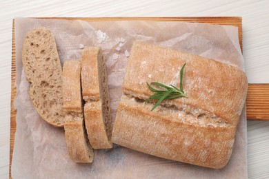 Photo of Fresh crispy ciabatta with rosemary on white wooden table, top view