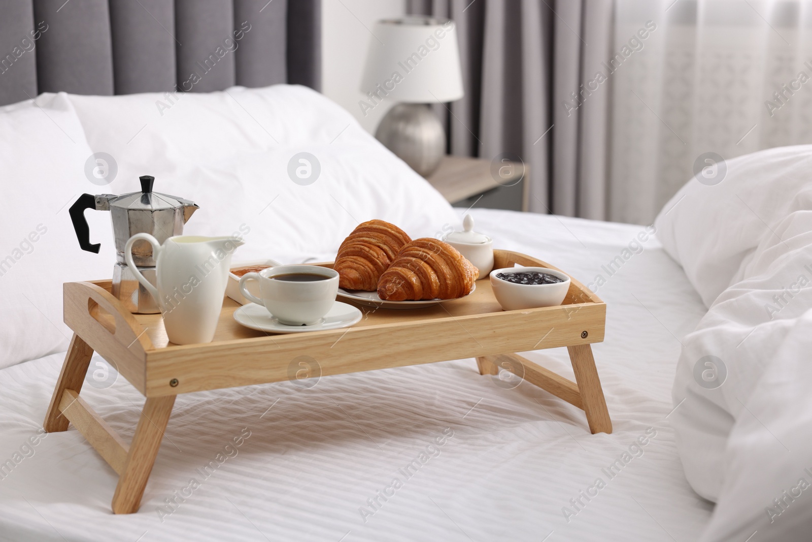 Wooden tray with tasty breakfast on bed at home Photo of Wooden tray with tasty breakfast on bed at home